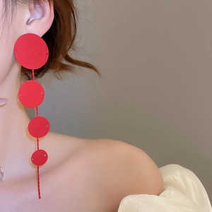 Macro detail of layered red circular earrings with spiral texture on the metallic surface