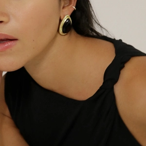 Gros plan détaillé d'une boucle d'oreille goutte en or avec pierre noire sur le mannequin