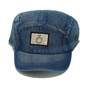 Close-up of washed blue denim five-panel hat with a short brim and metal ring detail.