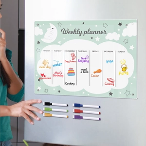Close-up of magnetic acrylic weekly calendar board with six colored markers on a fridge