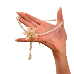 Elegante Perlenkette mit einer perlenbesetzten Blume und silbernen Quastenanhängern.