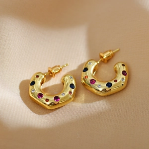 Detailed macro view of gold C-shaped hoop earrings with colorful inlaid rhinestones
