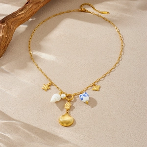 Gold stainless steel starfish and seashell pendant necklace on a sandy texture