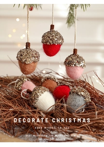 Detailed view of handmade wool felt acorns with glitter caps and festive hanging cords