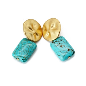 Detail view of bohemian turquoise drop earrings with gold hammered metal and long tassels