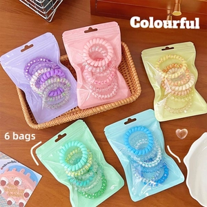 Pack of 6 colorful spiral hair ties in gradient shades and floral patterns on wood background