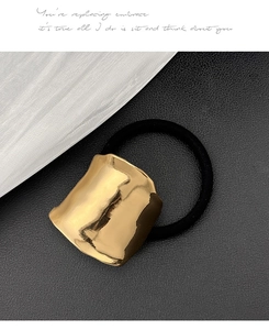 Detail eines minimalistischen goldenen Metall-Haargummis auf schwarzem Lederhintergrund