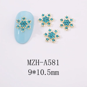 Détail macro de charmes d'ongles flocon dorés avec strass bleus et dimensions exactes