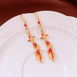 Detail of koi fish earrings with red enamel and gold finish on ceramic display