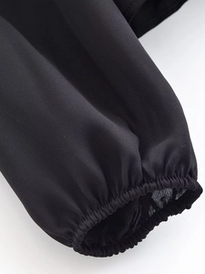 Detailed view of elastic smocked cuffs on a black French vintage long sleeve blouse