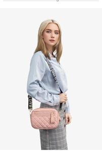 Pink quilted crossbody camera bag with polka dot wide strap on a female model