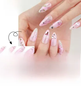 Detail of almond pink gradient press-on nails with bow designs and heart rhinestones