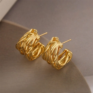 Macro detail of gold-plated geometric C-shape earrings with layered metallic wire texture
