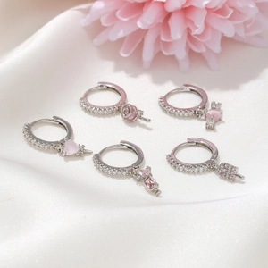 Detailed close-up of a five-piece zircon earring set with pink heart and floral motifs