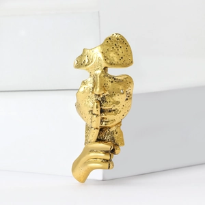 Artistic gold mask brooch with hush gesture on white blocks for suit and sweater