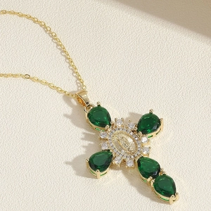 Macro shot of gold cross necklace with green drop gemstones and sparkling zircon detail