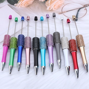 Macro detail of eleven colorful DIY diamond beaded pens on a white plush background