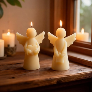 Close-up of two warm cream angel candles holding heart and star shapes on a wooden desk