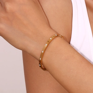 Detail of 18K gold plated stainless steel bangle with inlaid white cubic zirconia stones