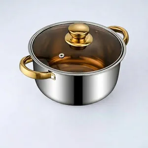 Polished stainless steel soup pot with golden handles and transparent glass lid