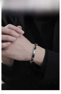 Detail of woven street style bracelet with silver metal chain and black leather on wrist