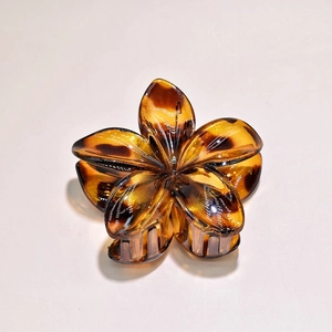 Detail of a resin plumeria flower hair claw clip with amber leopard tortoiseshell pattern