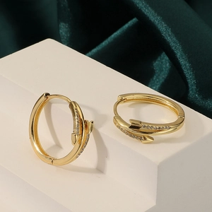 Macro shot of gold-plated arrow earrings with micro-set zircons on luxury silk