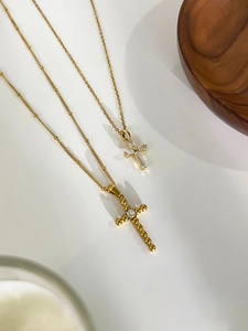 Close-up of golden titanium steel cross necklaces with zircon inlays and detailed texture
