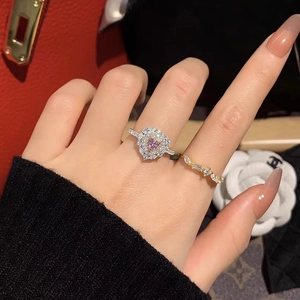 Dettaglio dell'anello con diamante rosa a cuore e fascia dorata su una mano femminile