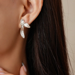 Detail view of silver earrings with artistic brushed metal texture on female model