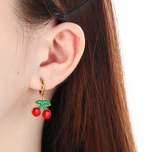 Gros plan de boucles d'oreilles cerises rouges en émail avec cerceaux dorés