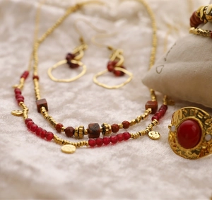 Détail d'un ensemble de colliers bohèmes dorés avec perles rouges et bijoux