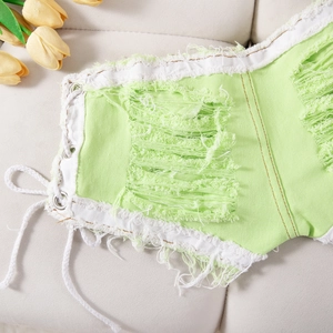 Primer plano de denim verde claro con bordes deshilachados y detalle de cordones