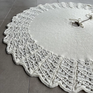 Close-up of white knitted Christmas tree skirt with hollow lace and wavy edges