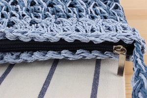 Detail shot of the sturdy navy zipper and hand-woven blue texture on a crossbody bag