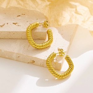 French vintage style twisted rope gold hoop earrings on a textured stone display