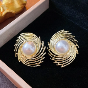 Detailed macro view of gold spiral earrings with elegant white pearl on black velvet