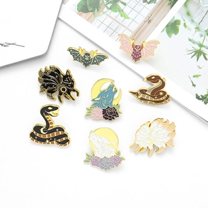 Detaillierte Emaille-Pins mit Wolfs- und Fledermausmotiven auf weißem Untergrund