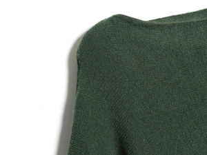 Détail d'un pull en maille vert foncé montrant la texture fine et le col bateau large