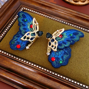 Détail de boucles d'oreilles papillon brodées vintage avec pierres en forme de coeur