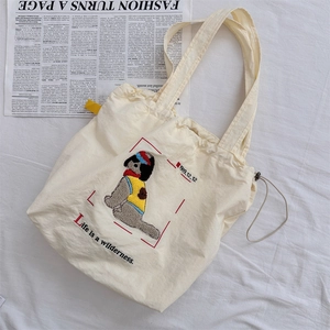 Detail of cute embroidered cartoon dog on off-white canvas tote bag with drawstring
