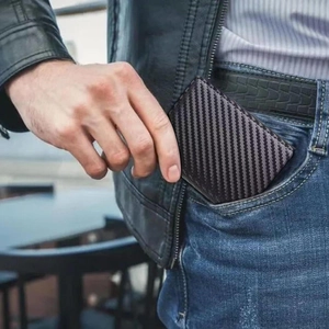 Slim carbon fiber RFID wallet for men being placed into a denim jeans pocket