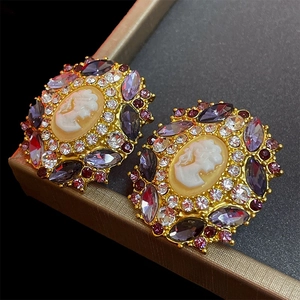 Vintage gold cameo earrings with purple rhinestones and intricate portrait relief detail