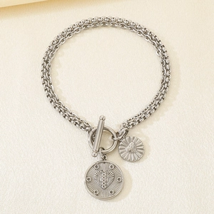Close-up of silver layered paperclip chain bracelet with heart pendants and T-bar clasp