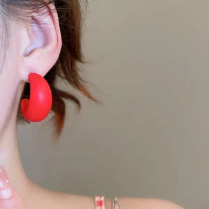 Close-up of matte red C-shaped acrylic earrings on model for a minimalist chic look