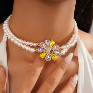 Close-up of double-layer pearl necklace with colorful gemstone flower pendant in gold