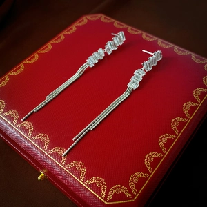 Close-up of silver tassel earrings with baguette-cut zircons on red jewelry box