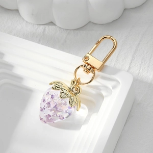 Detailed macro of strawberry keychain with gold D-buckle and purple crystal filler