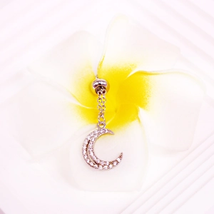 Macro shot of silver crescent moon belly button ring with rhinestones on a plumeria flower
