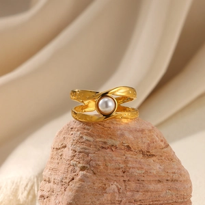 Golden hollow stainless steel pearl ring displayed on natural red stone with beige cloth